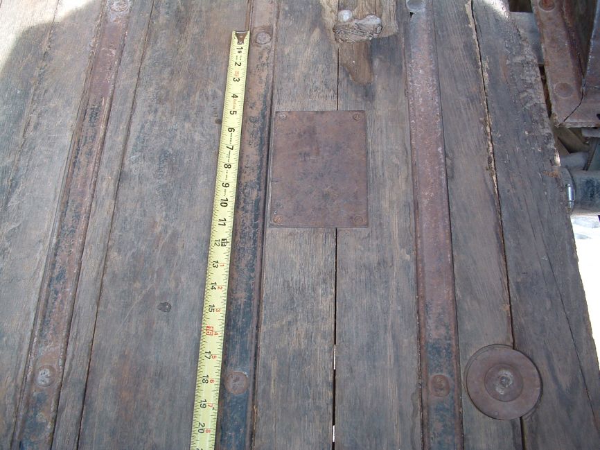 Fuel tank float access plate - location.
Image showing location of access plate in relationship to the skid strip mounting bolts found to the plate's immediate left (driver's side). 

Note what appears to be cracks in the bed wood. These are not cracks but actually joints between random width bed boards. The joints do not necessarily run parallel to the bed strips in all cases.
